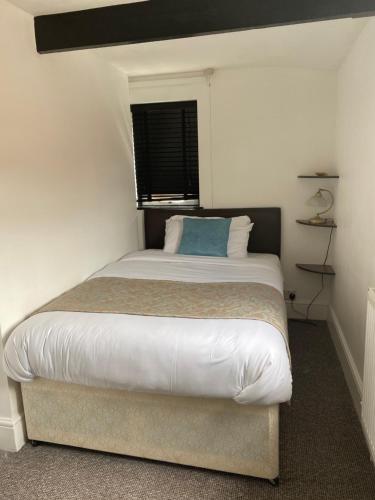 a bedroom with a bed with a blue pillow on it at The Tudor Hotel in Bridgwater