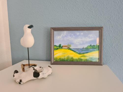 a table with a lamp and a painting on the wall at Jugendtours-Feriendorf Ummanz in Ummanz