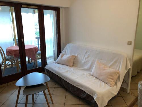 - une chambre avec un lit avec des draps blancs et une table dans l'établissement Soleil Levant, à Villers-sur-Mer