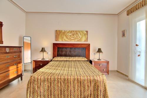 a bedroom with a bed and two dressers and two lamps at Casa Felicidad in Calpe