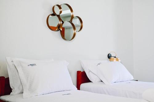 two beds with white sheets and a gold trophy on the wall at JJ Rooms luxury apartments in Kallithea Halkidikis