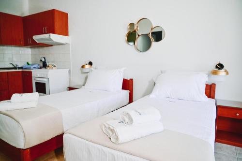 two beds in a room with a kitchen at JJ Rooms luxury apartments in Kallithea Halkidikis