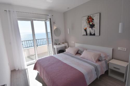 a white bedroom with a bed and a balcony at Villa NEDE 2 in Podgora