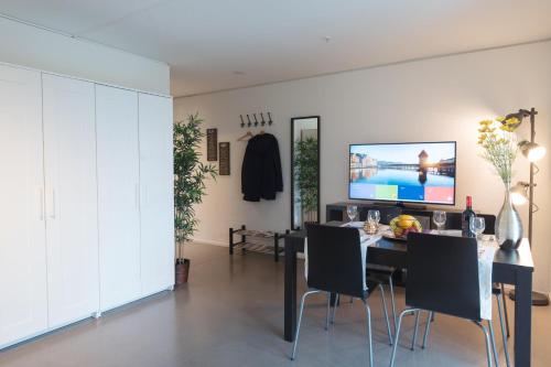 una sala da pranzo con tavolo, sedie e TV di HITrental Allmend Comfort Apartments a Lucerna