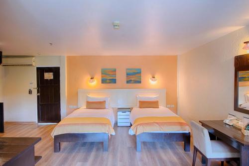 a bedroom with two beds and a table and a desk at Vacation Village Phra Nang Inn - SHA Extra Plus in Ao Nang Beach
