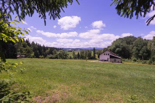 a large field with a barn in the distance at Baumzelt im Wald in Regen