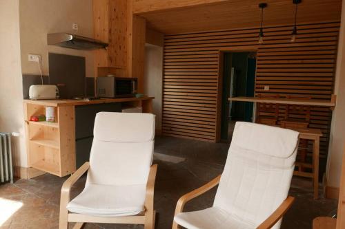 - deux chaises blanches dans une chambre avec cuisine dans l'établissement Joli appartement confortable rénové style cosy, à Saint-Martin-de-la-Porte