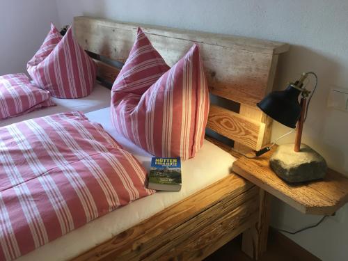 una cama con almohadas rosas y un libro sobre una mesa en Ferienwohnung Sundratn, en Wackersberg