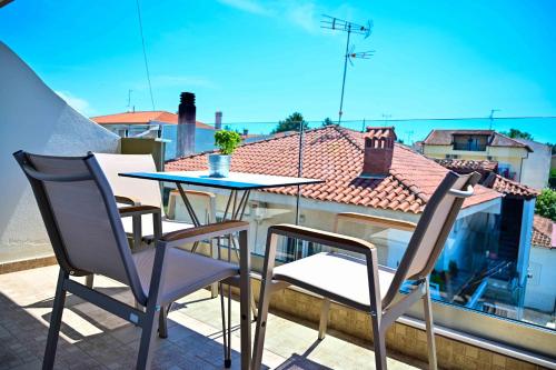 a table and chairs on a balcony with a view of a roof at JJ Rooms luxury apartments in Kallithea Halkidikis