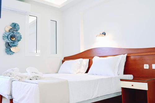 a bedroom with a white bed with a wooden headboard at JJ Rooms luxury apartments in Kallithea Halkidikis