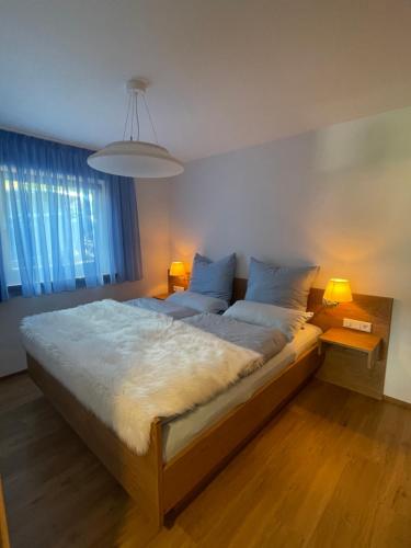 - une chambre avec un grand lit, deux lampes et une grande fenêtre dans l'établissement Landhaus Renata - Wendelstein, à Bayrischzell
