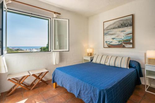 a bedroom with a blue bed and a large window at Bini S Aigo in Binibeca