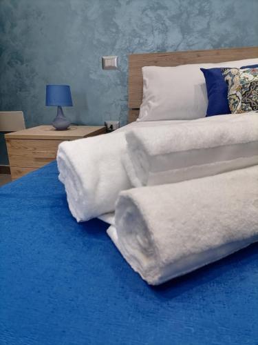 un grande letto con lenzuola bianche e una coperta blu di BeB Coccinella a Porto Cesareo