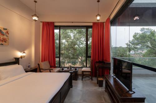 a bedroom with a bed and a large window at Triose Boutique Hotel Lonavala in Lonavala
