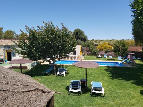a yard with chairs and umbrellas and a swimming pool at Los Duendes in El Puerto de Santa María