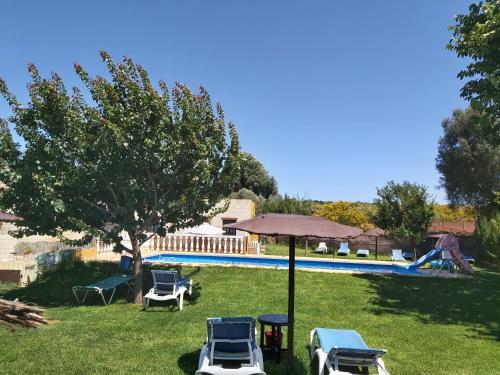 a yard with chairs and an umbrella and a pool at Los Duendes in El Puerto de Santa María