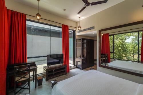 a bedroom with red curtains and a bed and a television at Triose Boutique Hotel Lonavala in Lonavala