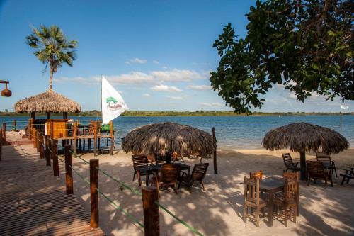 a beach with chairs and tables and straw umbrellas at Pousada Flambaião in Jijoca de Jericoacoara