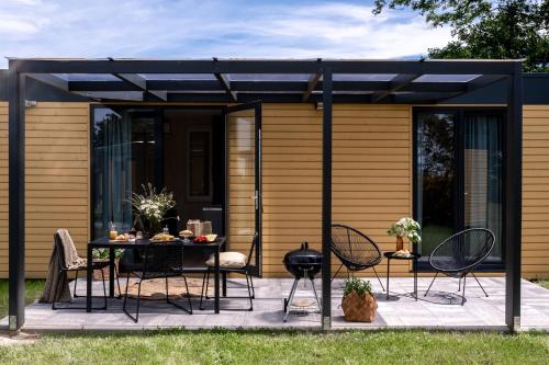 a black pergola on a patio with a table and chairs at ZATORHOUSE in Zator