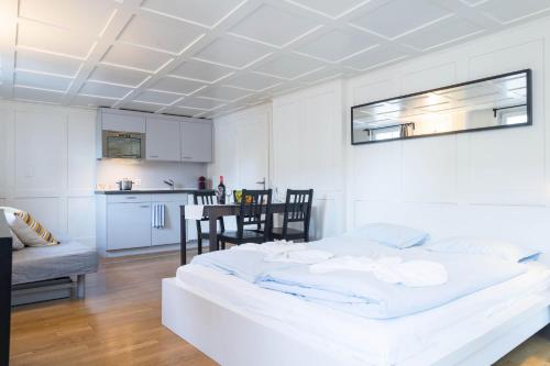 een slaapkamer met een groot wit bed en een keuken bij HITrental Zeughausgasse - Apartment in Zug