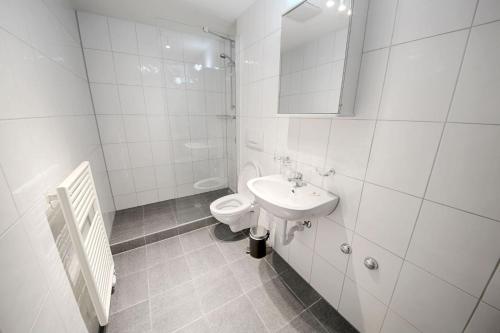 a white bathroom with a toilet and a sink at HITrental Oerlikon Apartments in Zürich