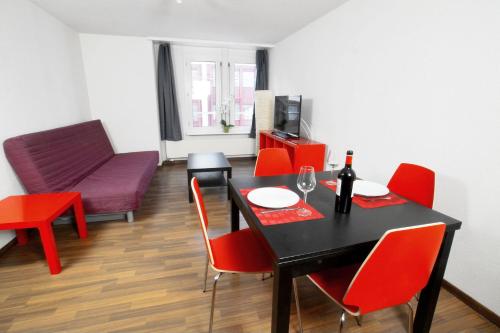 a dining room with a table and red chairs at HITrental Oerlikon Apartments in Zürich