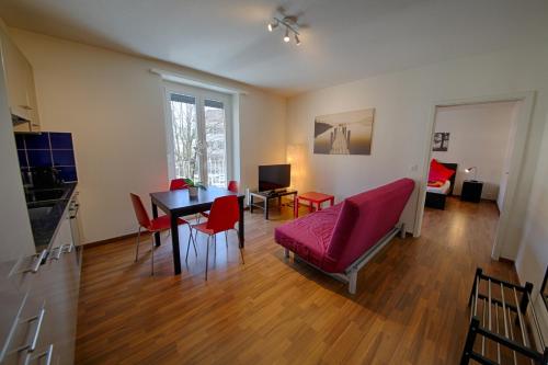 チューリッヒにあるHITレンタル エリコン アパートメンツのリビングルーム(テーブル、赤い椅子付)