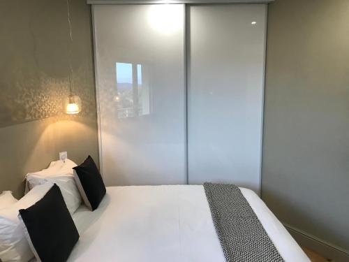 une chambre avec un grand lit blanc avec des oreillers noirs dans l'établissement Appartements de Standing - Panate, à Corte