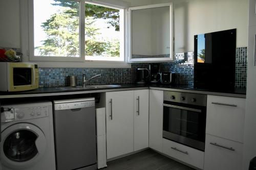 une cuisine avec des armoires blanches et une laveuse et une sécheuse dans l'établissement Charmante maison à 500 m de la côte, pour 4, à Notre-Dame-de-Monts