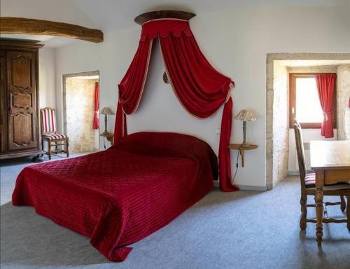 a bedroom with a red bed with a red canopy at La Maison Royale in Pesmes