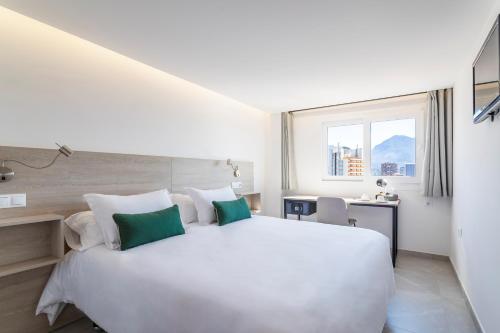 a white bedroom with a large bed and a window at Halley Hotel & Apartments Affiliated by Meliá in Benidorm