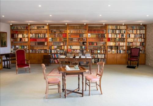 biblioteca con mesa, sillas y estanterías en La Maison Royale en Pesmes