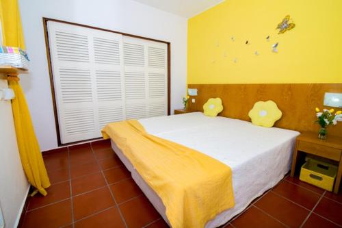 a bedroom with a bed with yellow walls and a window at Pé na Praia by OCvillas in Albufeira
