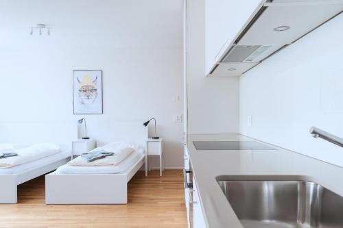 a white bathroom with a sink and a tub at HITrental Messe Apartments in Basel