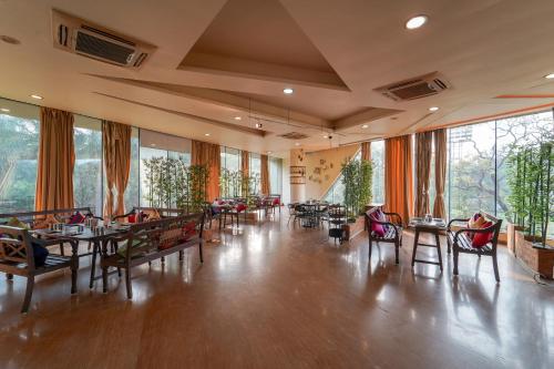 a restaurant with tables and chairs and large windows at Triose Boutique Hotel Lonavala in Lonavala