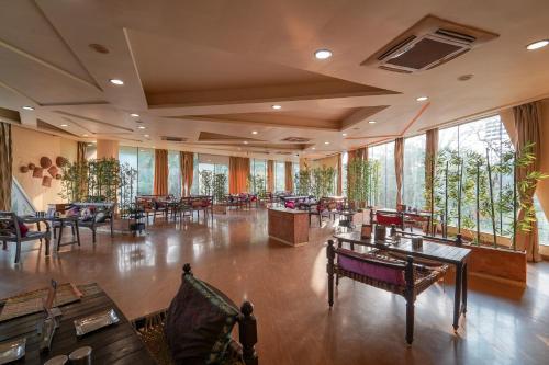 a restaurant with tables and chairs and large windows at Triose Boutique Hotel Lonavala in Lonavala