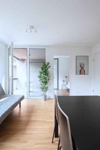 a white living room with a table and a couch at HITrental Messe Apartments in Basel