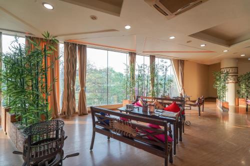 a living room with a table and chairs and large windows at Triose Boutique Hotel Lonavala in Lonavala