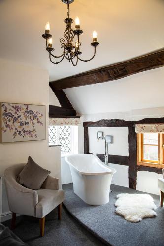 a bathroom with a tub and a chair and a chandelier at The Yew Tree Inn in Church Stretton