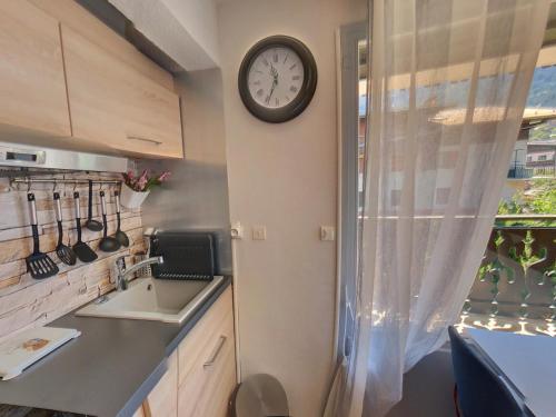 Una cocina con un fregadero y un reloj en la pared. en Studio centre Carroz CA210, en Les Carroz d'Araches