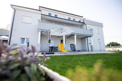 a building with a patio with chairs and an umbrella at Apartments Luka in Senj