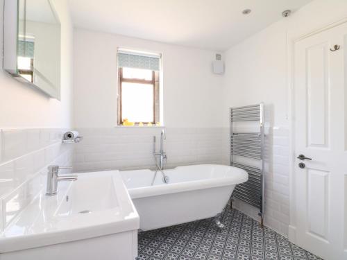 a white bathroom with a tub and a sink at Well Cottage in Cheltenham