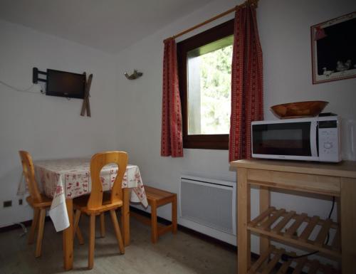 - une cuisine avec une table, un four micro-ondes et des chaises dans l'établissement AG005 - Studio coin montagne proche pistes, aux Carroz d'Arâches