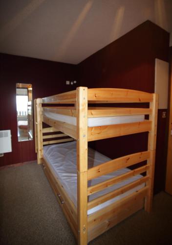 Ce lit superposé en bois se trouve dans un dortoir. dans l'établissement AG005 - Studio coin montagne proche pistes, aux Carroz d'Arâches
