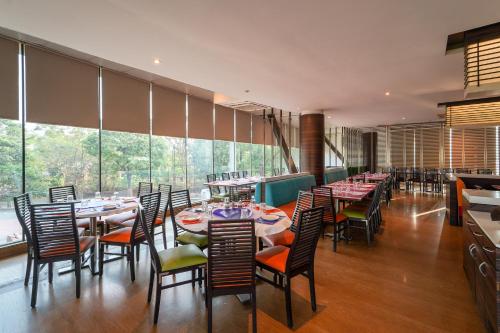 a restaurant with tables and chairs and large windows at Triose Boutique Hotel Lonavala in Lonavala