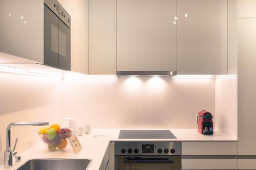 a kitchen with white cabinets and a bowl of fruit on the counter at HITrental Town Hall Apartments in Basel