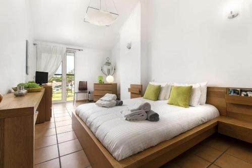 Vila Sol Resort 2 Bedroom Family Apartment في كوارتيرا: غرفة نوم بسرير ذو شراشف بيضاء ومخدات خضراء