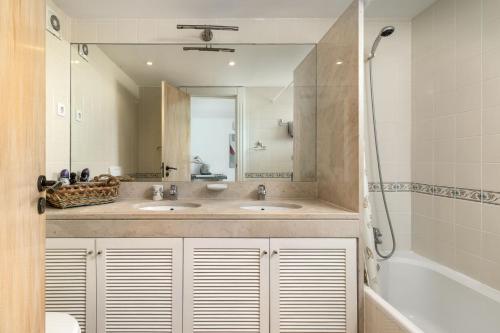Vila Sol Resort 2 Bedroom Family Apartment في كوارتيرا: حمام به مغسلتين وحوض استحمام ومرآة