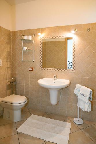 a bathroom with a sink and a toilet and a mirror at Le Dune in San Teodoro