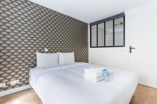 une chambre avec un lit blanc avec des serviettes dessus dans l'établissement Appartement Duplex de Charme proche de l'opéra Garnier, à Paris